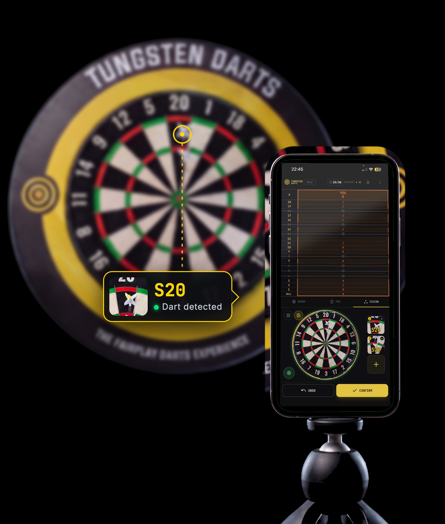 A phone on a small tripod in front of a Tungsten Darts dartboard, the app showing a dart detected in the 20